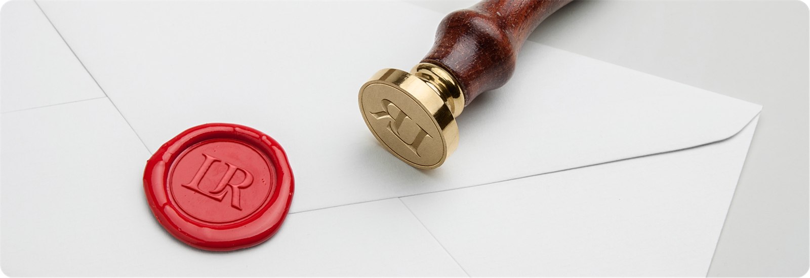 Red wax seal stamped with the LR monogram beside a brass wax stamp
